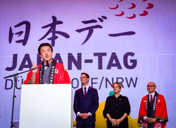 Japan-Tag 2026 in Düsseldorf, einzigartiges Kulturfest in der Landeshauptstadt von NRW - Takao Hariya, Präsident des japanischen Clubs in Düsslddorf bei seienr Begrüssungsrede - im Hitergrund stehen NRW Ministerpräsident Hendrik Wüst, NRW Ministerin für Wirtschaft und Kultur Mona Neubaur und der japanische Generalkonsul für Düsseldorf Yoshitaka Tsunoda auf der Bühne zur Begrüssung Düsseldorf Burgplatz NRW Deutschland *** Japan Day 2026 in Düsseldorf, unique cultural festival in the state capital of NRW Takao Hariya, President of the Japanese Club in Düsseldorf during his welcoming speech in the background are NRW Minister President Hendrik Wüst, NRW Minister for Economic Affairs and Culture Mona Neubaur and the Japanese Cons