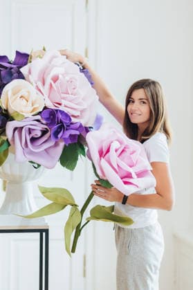 Junge Frau arrangiert übergroße künstliche Blumen im hellen Studio-Innenraum Young woman arranges oversized artificial flowers in bright studio interior (License=RF) ,model released, Symbolfoto Copyright: xZoonar.com ViorelxKurnosovx 25053109 ,model released, Symbolfoto ,property released