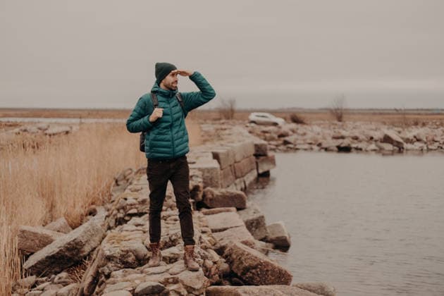 Male Reisende mit Rucksack sieht über den See von felsigen Küste bei kaltem Wetter Male traveler with backpack looks across lake from rocky shoreline in cold weather (License=RF) ,model released, Symbolfoto Copyright: xZoonar.com ViorelxKurnosovx 25053118 ,model released, Symbolfoto ,property released