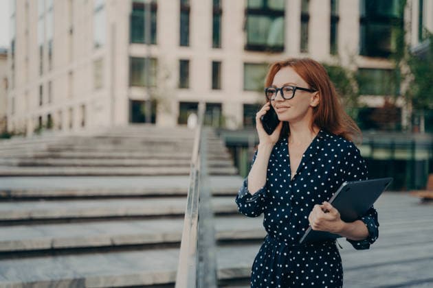 Geschäftsfrau spricht über Smartphone und hält Tablet außerhalb des modernen Bürogebäudes Businesswoman talking on smartphone while holding tablet outside modern office building (License=RF) ,model released, Symbolfoto Copyright: xZoonar.com ViorelxKurnosovx 25062891 ,model released, Symbolfoto ,property released