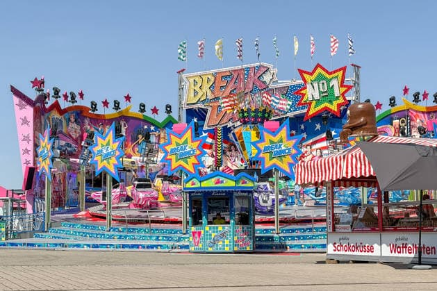 Freiburg im Breisgau GER, Jahrmarktbetrieb, Freiburg im Breisgau, 24.05.2026 Ein Break-Dance-Fahrgeschäft mit bunten Lichtern und Dekorationen, darunter der Schriftzug Welcome to Fabulous Las Vegas Nevada, steht auf einem Jahrmarkt. Rechts daneben befindet sich ein Verkaufsstand für Süßigkeiten wie Schokoküsse und Waffeltüten, gekrönt von einer großen Schokoladenfigur. Der Himmel ist klarblau. *** Freiburg im Breisgau GER, Fairground operation, Freiburg im Breisgau, 24 05 2026 A break dance ride with colorful lights and decorations, including the lettering Welcome to Fabulous Las Vegas Nevada, stands on a fairground To the right of it is a stall selling sweets such as chocolate kisses and waffle cones, topped by a large choc Copyright: xEibner-Pressefoto ThomasxHessx