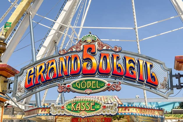 Freiburg im Breisgau GER, Jahrmarktbesuch, Freiburg im Breisgau, 24.05.2026 Das farbenfrohe Schild des Riesenrads Grand Soleil von Göbel mit den Aufschriften Kasse , Bienvenue! und Bon Voyage! ist vor klarem blauem Himmel zu sehen. *** Freiburg im Breisgau GER, Fair visit, Freiburg im Breisgau, 24 05 2026 The colorful sign of the Grand Soleil Ferris wheel by Göbel with the inscriptions Kasse , Bienvenue and Bon Voyage can be seen in front of a clear blue sky Copyright: xEibner-Pressefoto ThomasxHessx