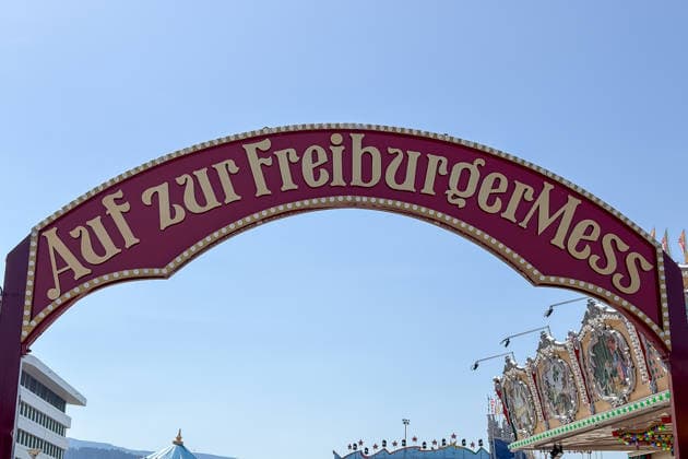 Freiburg im Breisgau GER, Freiburger Mess, Freiburg im Breisgau, 24.05.2026 Der Eingangstorbogen zur Freiburger Mess unter blauem Himmel, flankiert von einem modernen Gebäude und einem Karussell. *** Freiburg im Breisgau GER, Freiburger Mess, Freiburg im Breisgau, 24 05 2026 The entrance archway to the Freiburger Mess under a blue sky, flanked by a modern building and a carousel Copyright: xEibner-Pressefoto ThomasxHessx
