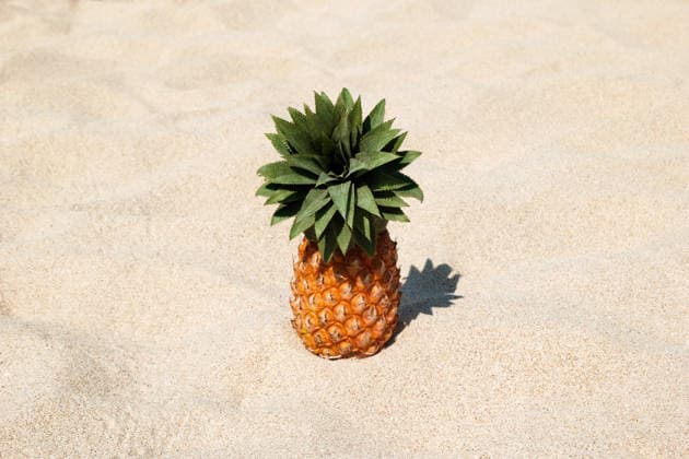 Eine Ananas am weißen Sandstrand an einem sonnigen Tag, mit Platz für Text. Pineapple on the white sand beach on a sunny day, with copy space. (License=RF) Copyright: xZoonar.com NadezhdaxZaitsevax 25068862