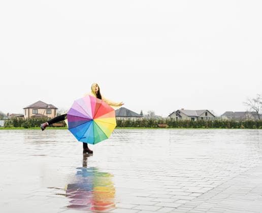 Eine schöne brünette Frau, die einen bunten Regenschirm hält und im Regen tanzt Beautiful brunette woman in yellow raincoat holding rainbow umbrella out in the rain (License=RF) ,model released, Symbolfoto Copyright: xZoonar.com ILONAxSHOROKHOVAx 25077121 ,model released, Symbolfoto ,property released