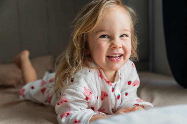 Smiling toddler girl in pajamas lying on bed, looking at camera Antalya, Antalya, Türkiye CR_BMEE260513-2016016-01 ,model released, Symbolfoto