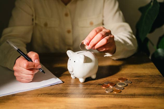 Woman planning budget while saving coins in piggy bank Corby, England, United Kingdom R_ATMT260513-2020087-01 ,model released, Symbolfoto