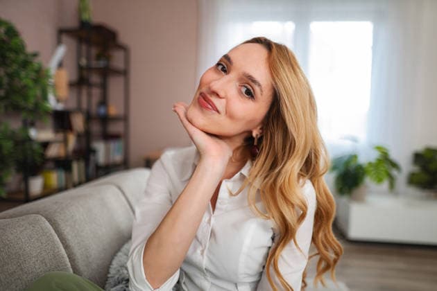 Eine Frau, die zu Hause auf dem Sofa sitzt, lächelt und sich entspannt Woman smiling, sitting on a sofa, and expressing positive emotions (License=RF) ,model released, Symbolfoto Copyright: xZoonar.com JelenaxCvetkovicx 25079974 ,model released, Symbolfoto ,property released