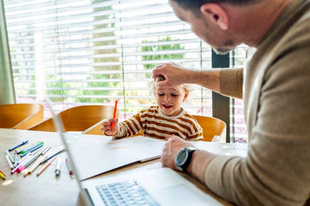 Remote working dad taking care of ill child during home office day. Father working from home while caring for sick toddler staying home from daycare. model released