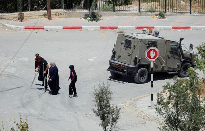 Israeli Demolition West Bank Family Displaced Eid Al-Adha Residents, including a man using a crutch and a medical worker, walk past an Israeli military vehicle in Nahhalin, occupied West Bank, on May 25, 2026, after a demolition operation. The demolition, carried out by Israeli forces who stated the structure was built without a permit, displaced an eight-member Palestinian family just two days before the Islamic holiday of Eid al-Adha. Bethlehem West Bank Palestinian Territories Copyright: xMosabxShawerx
