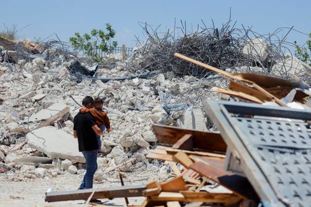 Israeli Demolition West Bank Family Displaced Eid Al-Adha A man carries a small child past the rubble of a destroyed building in Nahhalin, occupied West Bank, on May 25, 2026. The demolition, carried out by Israeli forces who stated the structure was built without a permit, displaced an eight-member Palestinian family just two days before the Islamic holiday of Eid al-Adha. Bethlehem West Bank Palestinian Territories Copyright: xMosabxShawerx