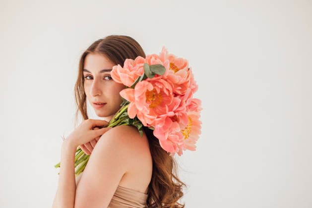Eine junge Frau mit langen braunen Haaren, die einen Strauß leuchtend rosa Pfingstrosen in den Händen hält, posiert anmutig vor einem sanften, neutralen Hintergrund und verkörpert Schönheit und Eleganz in der Blumenkunst Female model with flowing hair, holding pink peony bouquet, poses against a soft background, showcasing natural beauty and elegance in floral arrangement (License=RF) ,model released, Symbolfoto Copyright: xZoonar.com DashaxPetrenkox 25102954 ,model released, Symbolfoto ,property released
