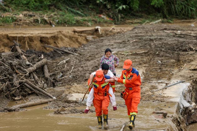 (260526) -- CHONGQING, May 26, 2026 -- Rescuers assist a villager passing through a waterlogged section at Yongchuan District of southwest China s Chongqing Municipality, May 26, 2026. From Saturday night to early Sunday morning, a sudden and extreme catastrophic rainstorm struck Yongchuan, triggering flash floods and geological disasters in multiple areas of this district. After the disaster occurred, the local authorities immediately activated the emergency response mechanism, coordinated rescue forces from all sides and made every effort to carry out rescue operations and infrastructure restoration. Rescue and response efforts are still underway. ) CHINA-CHONGQING-FLOOD-RESCUE (CN) HuangxWei 