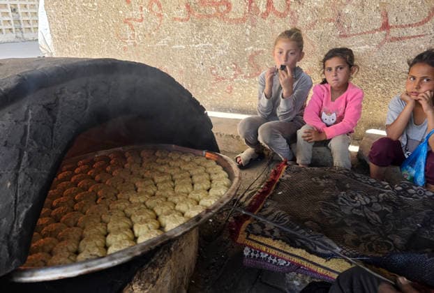 Displaced Palestinian family bakes Eid cakes inside shelter in Khan Younis A displaced Palestinian family prepares and bakes traditional Eid cakes on makeshift ovens inside a tent at a shelter center in Khan Younis in the southern Gaza Strip on May 26, 2026, ahead of Eid al-Adha. Palestinian families are trying to preserve holiday traditions and bring joy to children despite the ongoing war and harsh living conditions. Photo by Tariq Mohammad APA Images Khan Yunis Gaza Strip Palestinian Territory 260526_Khan_Yunis_TM_02(24) Copyright: xapaimagesxTariqxMohammad xapaimagesx
