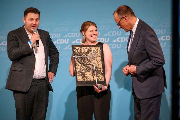 27.05.2026, Politik, Bundeskanzler Friedrich Merz (CDU) bekommt ein Geschenk - das Stadtblid - zu Gast als Festredner beim Festakt in der Schützenhalle Hüsten bei Arnsberg. 80 Jahre Neheim-Hüstener Programm. Nordrhein-Westfalen Deutschland *** 27 05 2026, Politics, Federal Chancellor Friedrich Merz CDU receives a gift the Stadtblid as guest speaker at the ceremony in the Schützenhalle Hüsten near Arnsberg 80 years of Neheim Hüstener program North Rhine-Westphalia Germany