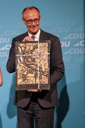 27.05.2026, Politik, Bundeskanzler Friedrich Merz (CDU) mit dem Geschenk - Ein Stadtbild - zu Gast als Festredner beim Festakt in der Schützenhalle Hüsten bei Arnsberg. 80 Jahre Neheim-Hüstener Programm. Nordrhein-Westfalen Deutschland *** 27 05 2026, Politics, Federal Chancellor Friedrich Merz CDU with the gift A cityscape as a guest speaker at the ceremony in the Schützenhalle Hüsten near Arnsberg 80 years of Neheim Hüstener program North Rhine-Westphalia Germany