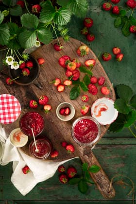 Flat lay of home made fresh strawberries jam in glass containers on wooden table and strawberry plants Flat lay of home made fresh strawberries jam in glass containers on wooden table and strawberry plants Copyright: xMonicaxBertolazzix MB130526-10