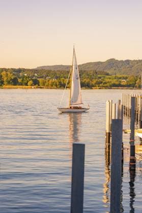 Ein Segelboot auf einem ruhigen See bei Abendstimmung und Bergsilhouette im Hintergrund, Lindau, Bodenseekreis, Deutschland A sailboat on a calm lake in the evening with mountain skyline in the background, Lindau, Bodenseekreis, Germany Copyright: imageBROKER ManuelxKamuf iblmlk17858013.jpg