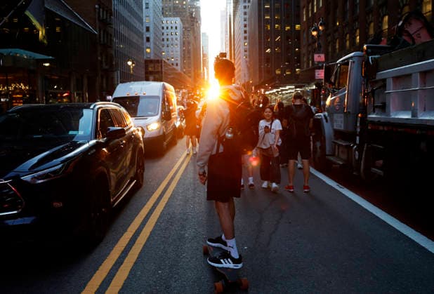 A skateboarder captures content with a cell phone while riding on 42nd street for a Manhattanhenge sunset event in New York City on Thursday, May 28, 2026. The Manhattanhenge sunset comes twice a year when the setting sun aligns precisely with Manhattan s street grid.  NYP20260528202 JohnxAngelillo