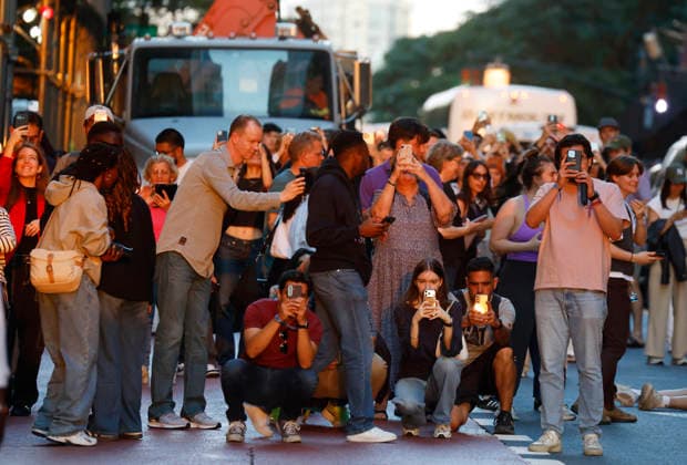Revelers holding cameras and cell phones stand on 42nd street with moving traffic for a Manhattanhenge sunset event in New York City on Thursday, May 28, 2026. The Manhattanhenge sunset comes twice a year when the setting sun aligns precisely with Manhattan s street grid.  NYP20260528208 JohnxAngelillo