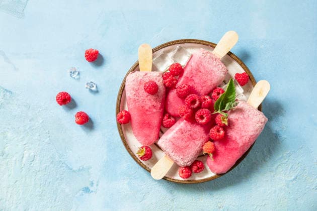 Ein Konzept für gesunde Sommergerichte: hausgemachtes Himbeereis. Vegane Himbeer-Milch-Eis am Stiel vor einem blauen Steinhintergrund. Blick von oben. Healthy summer food concept, homemade raspberry ice cream. Vegan raspberry milk popsicles on a blue stone background. View from above. (License=RF) Copyright: xZoonar.com ELENAxHRAMOVAx 25108460