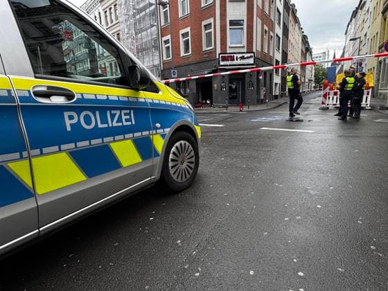 Polizeiwagen vor einer abgesperrten Straße am Friesenwall in Köln. Mehrere Polizisten stehen hinter einer rot-weißen Absperrung vor der Bar mit angeschaltetem Warnblinker. *** Police car in front of a cordoned-off street on Friesenwall in Cologne Several police officers stand behind a red and white barrier in front of the bar with their hazard lights on