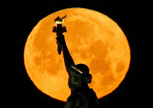 A rare Blue Moon, the second full moon to appear in the sky in a single month, sets behind the Statue of Liberty on Sunday, May 31, 2026 in New York City.  NYP20260531105 JOHNxANGELILLO