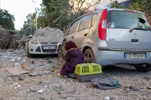 A girl looks at a smartphone while sitting among the rubble by a car and a pet carrier outside a nine-storey apartment building in the Podilskyi district, damaged by a massive Russian missile and drone attack, Kyiv, Ukraine, on 2 June 2026. The overnight strike killed six people and injured 79, including three children, in the Ukrainian capital. In the Podilskyi district, residential buildings, a garage cooperative, a communal enterprise, and a four-storey educational institution sustained damage as a result of the attack. (Photo by Kyrylo Chubotin Ukrinform) Aftermath of Russian overnight attack in Kyiv’s Podilskyi district  Copyright: xKirillxChubotinx