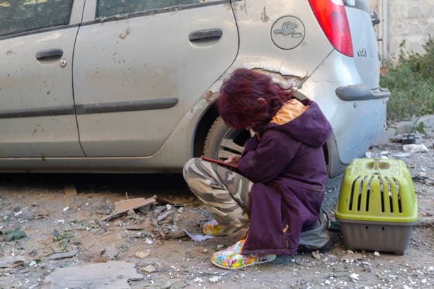 A girl looks at a smartphone while sitting among the rubble by a car and a pet carrier outside a nine-storey apartment building in the Podilskyi district, damaged by a massive Russian missile and drone attack, Kyiv, Ukraine, on 2 June 2026. The overnight strike killed six people and injured 79, including three children, in the Ukrainian capital. In the Podilskyi district, residential buildings, a garage cooperative, a communal enterprise, and a four-storey educational institution sustained damage as a result of the attack. (Photo by Kyrylo Chubotin Ukrinform) Aftermath of Russian overnight attack in Kyiv’s Podilskyi district  Copyright: xKirillxChubotinx