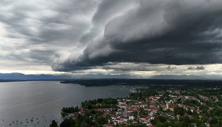 Ein Frühsommertag in Tutzing (Landkreis Starnberg). Hier der Blick über die Ortschaft und den Starnberger See mit der Alpenkette am Horizont, wo gerade ein Unwetter aufzieht, drüberzieht, eine Wolkenwand, Gewitterwalze, Wolkenrolle, Gewitterfront, Gewitterrolle, Unwetterfront, dunkle Wolken, Wetterbild *** An early summer day in Tutzing, Starnberg district Here the view over the village and Lake Starnberg with the Alps on the horizon, where a thunderstorm is just coming up, a wall of clouds, thunderstorm roll, cloud roll, thunderstorm front, thunderstorm roll, thunderstorm front, dark clouds, weather picture