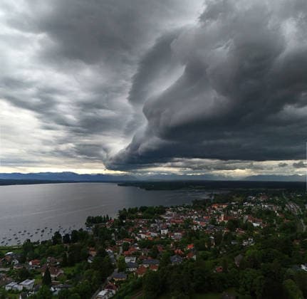 Ein Frühsommertag in Tutzing (Landkreis Starnberg). Hier der Blick über die Ortschaft und den Starnberger See mit der Alpenkette am Horizont, wo gerade ein Unwetter aufzieht, drüberzieht, eine Wolkenwand, Gewitterwalze, Wolkenrolle, Gewitterfront, Gewitterrolle, Unwetterfront, dunkle Wolken, Wetterbild *** An early summer day in Tutzing, Starnberg district Here the view over the village and Lake Starnberg with the Alps on the horizon, where a thunderstorm is just coming up, a wall of clouds, thunderstorm roll, cloud roll, thunderstorm front, thunderstorm roll, thunderstorm front, dark clouds, weather picture