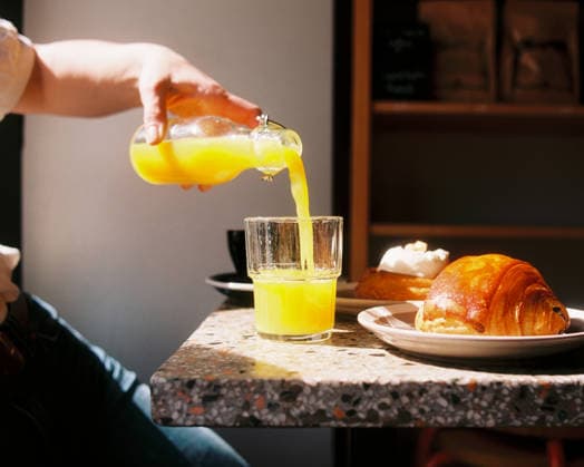 Hand pouring orange juice at sunny cafe breakfast Stockholm, Stockholm County, Sweden R_RABE260602-2038653-01 ,model released, Symbolfoto