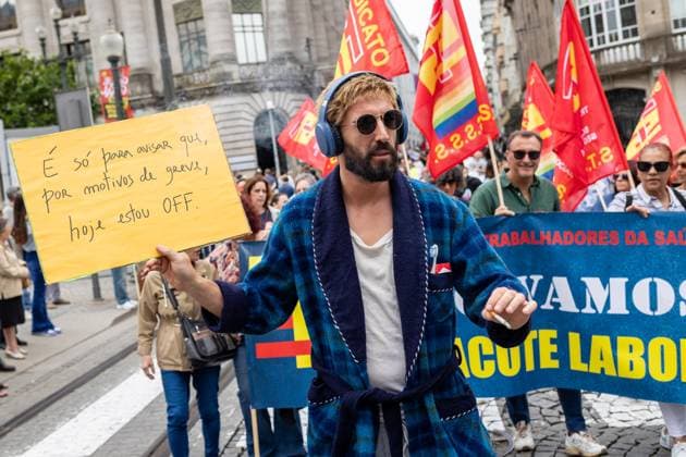 National General Strike in Porto, Portugal - 03 Jun 2026 A protester holds a handwritten placard while marching during the national general strike. Demonstrators gathered at Praça da Batalha and Avenida dos Aliados for a national general strike. Union groups, workers and supporters marched with banners, flags and handwritten signs criticizing the government’s proposed labour reforms and calling for improved working conditions, higher wages and stronger public services. The protest featured megaphones, flares and visual messages reflecting broad mobilization across the city. Porto Portugal Copyright: xDiogoxBaptistax xSOPAxImagesx DB_20260603GREVEGERALPORTO_0020