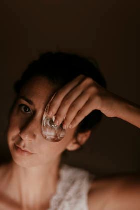 Woman holding a glass prism over her eye indoors model released, Symbolfoto, GMLF01659