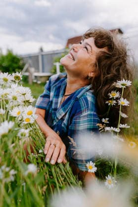 Smiling woman looking up among daisies in a summer garden model released, Symbolfoto, IEF00836