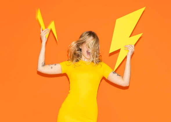 Model in yellow dress holding paper lightning bolt with high energy model released, Symbolfoto, MIKF00905