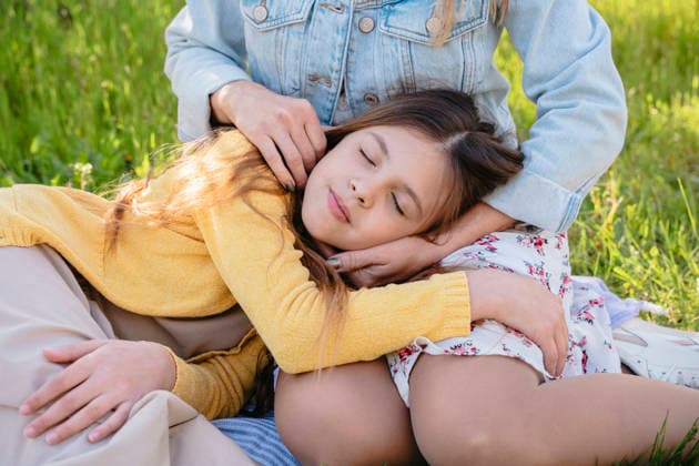 Mother and daughter hugging and sleeping in a spring meadow model released, Symbolfoto, NLAF00766