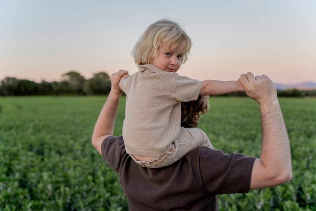 Father carrying kid on shoulders in a green field at sunset model released, Symbolfoto, OGSF00295