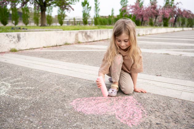 Child drawing a pink heart with chalk on the pavement outdoors model released, Symbolfoto, OGSF00330