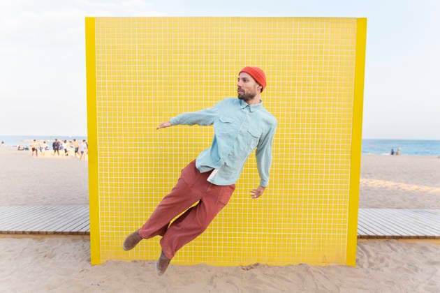 Energetic superhero jumping by a yellow tiled wall on the beach model released, Symbolfoto, YPF00272