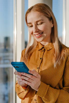 Smiling businesswoman using smartphone by office window model released, Symbolfoto property released, YTF04863
