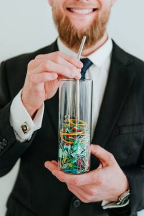 Smiling businessman holding glass of stationery with a straw model released, Symbolfoto property released, YTF04867