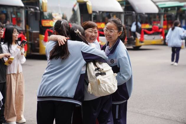 (260607) -- BEIJING, June 7, 2026 -- Students hug a teacher before taking bus to national college entrance examination sites in Qinyang, central China s Henan Province, June 7, 2026. This year s national college entrance exam, also known as the gaokao, kicked off Sunday nationwide. (Photo by Xinhua) CHINA-COLLEGE ENTRANCE EXAMINATION (CN) ZhangxXinyu 