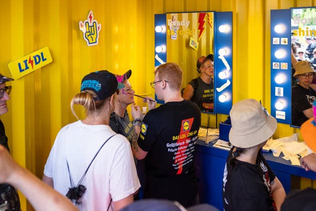 Musikfestival Rock im Park 2026, Nürnberg, 07.06.2026 Ein Lidl-Mitarbeiter schminkt eine Festivalbesucherin an der Schminkbox im Lidl Rock Store. Beleuchtete Spiegel und gelbe Containeroptik praegen den Markenauftritt. Nürnberg Bayern Deutschland *** Music festival Rock im Park 2026, Nuremberg, 07 06 2026 A Lidl employee applies make-up to a festival visitor at the make-up box in the Lidl Rock Store Illuminated mirrors and yellow container optics characterize the brand appearance Nuremberg Bavaria Germany 20260607-286A8406-M4000