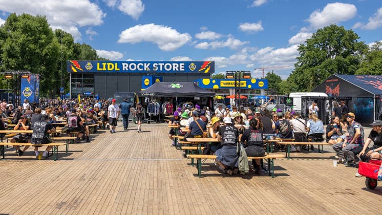 Musikfestival Rock im Park 2026, Nürnberg, 07.06.2026 Festivalbesucher sitzen bei sonnigem Wetter an Biertischgarnituren auf dem Gelaende. Im Hintergrund der Lidl Rock Store mit Merchandising-Staenden und weiteren Verkaufszelten. Nürnberg Bayern Deutschland *** Music festival Rock im Park 2026, Nuremberg, 07 06 2026 Festival visitors sit at beer table sets on the grounds in sunny weather In the background the Lidl Rock Store with merchandising stands and other sales tents Nuremberg Bavaria Germany 20260607-286A8422-M4000