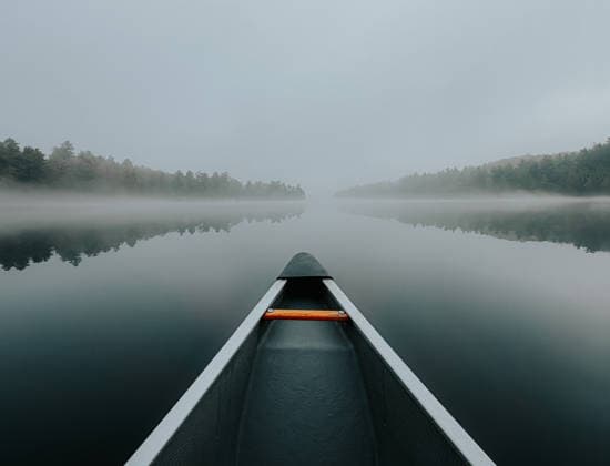 Canoe gliding through fog on a still lake with shoreline in background Buck Lake, Ontario, Canada CR_DOHO260604G-2040771-01
