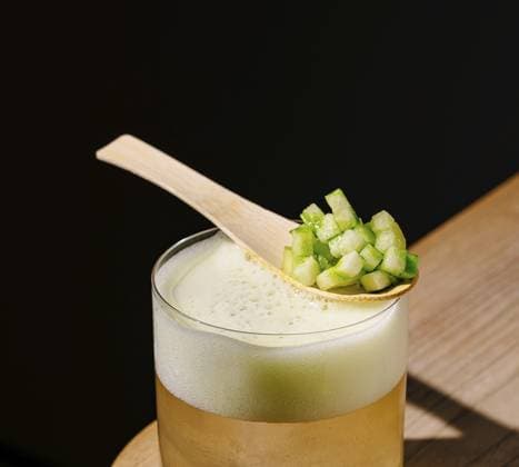 Food, Ein klares Getränk, das in einem Glas serviert wird, steht auf einer Holzoberfläche. Ein Holzlöffel mit fein gehacktem grünem Gemüse ruht auf dem Glas und verleiht dem Getränk eine frische Note Food, A clear beverage served in a glass sits on a wooden surface. A wooden spoon with finely chopped green vegetables rests on the glass, adding a fresh touch to the drink Copyright: imageBROKER AntonxDobrea ibxiqx17838674.jpg