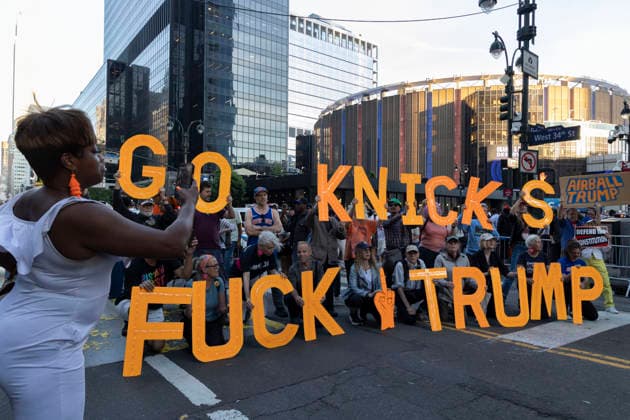 June 8, 2026, New York, New York, USA: A Knicks fan takes a photo of protesters holding letters that read GO KNICKS FUCK TRUMP and signs that read AIRBALL TRUMP outside Madison Square Garden as fans enter the stadium for game 3 of the NBA finals. Security is high in Midtown Manhattan with street closures, portable fences, barricades and heavy police presence for President Trump s attendance at the basketball game. New York USA - ZUMAr174 20260608_znp_r174_002 Copyright: xGinaxMxRandazzox
