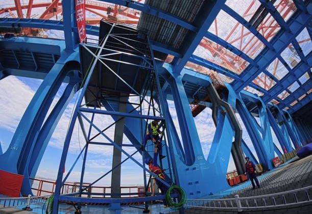 (260609) -- SHANGHAI, June 9, 2026 -- Workers climb scaffolding to fasten bolts at the construction site of the Chongqi Highway-Railway Bridge over the Yangtze River between east China s Shanghai and Jiangsu, June 9, 2026. A key project of the Shanghai-Chongqing-Chengdu high-speed railway, the Chongqi Highway-Railway Bridge was successfully closed here on Tuesday. It has a total length of 4.09 kilometers and a main span of 400 meters. Once opened to traffic, the bridge will reduce the travel time between Shanghai and Qidong of Jiangsu from two and a half hours to less than half an hour. ) CHINA-SHANGHAI-JIANGSU-CHONGQI HIGHWAY-RAILWAY BRIDGE OVER YANGTZE RIVER (CN) FangxZhe 