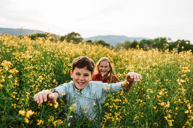 Happy siblings running through spring field and enjoying nature together. Happy siblings running through spring blooming field and enjoying nature together. model released